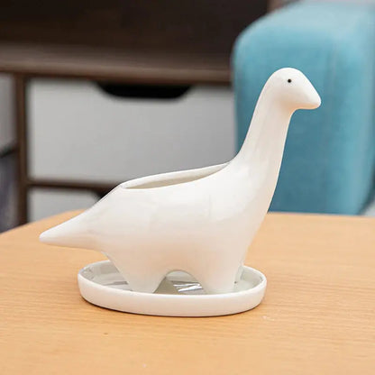 a white ceramic bird sitting on top of a wooden table