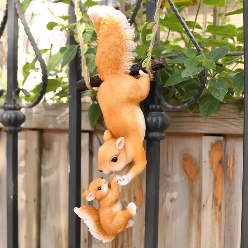 a squirrel and her babies hanging from a fence