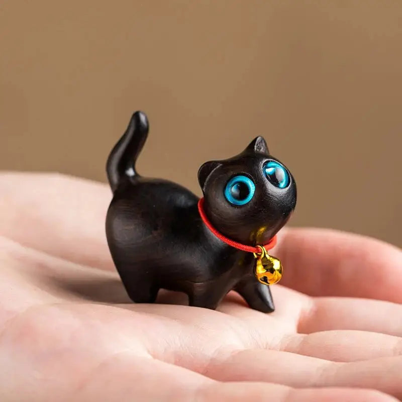 a small black cat figurine on a person's hand