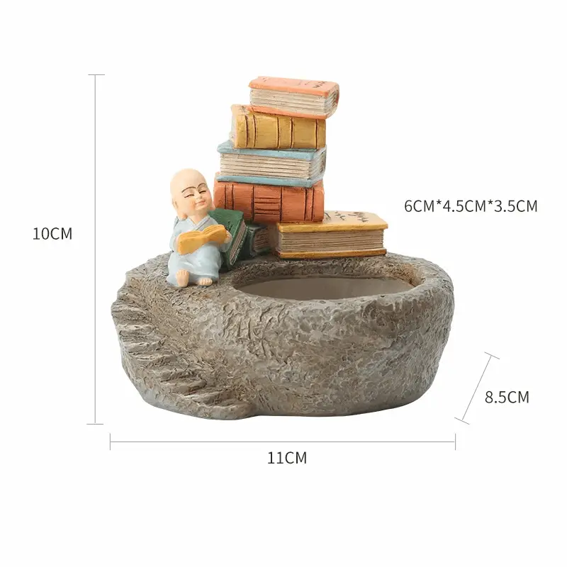 a small statue of a baby sitting on a rock with books on top of it