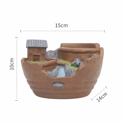 a clay pot with a house on top of it