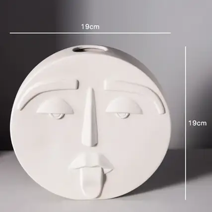 a white face vase with a face drawn on it