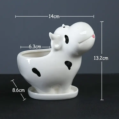 a white ceramic animal shaped planter with black spots