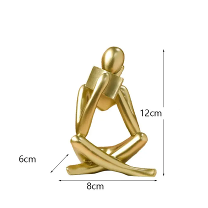 a gold plated figurine sitting on a white background