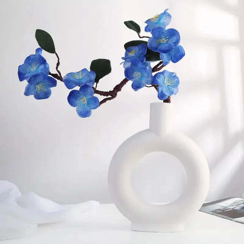 a white vase with blue flowers in it