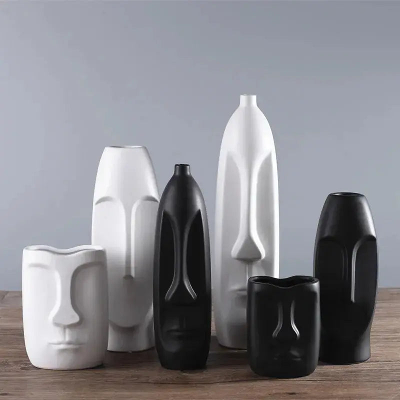 a group of black and white vases sitting on top of a wooden table