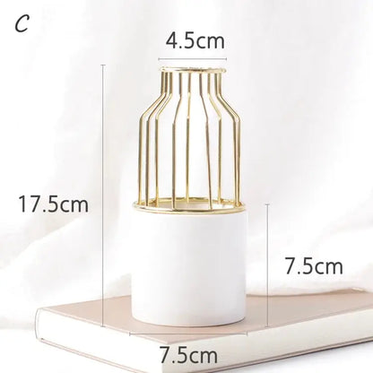 a white vase with a gold cage on top of it