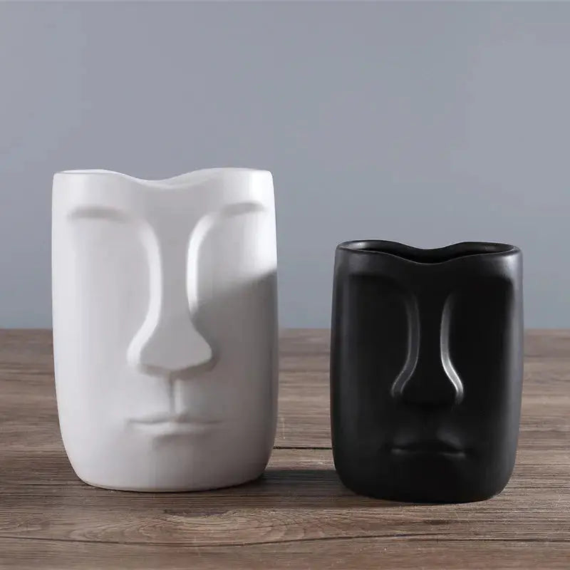 two black and white vases sitting on a wooden table