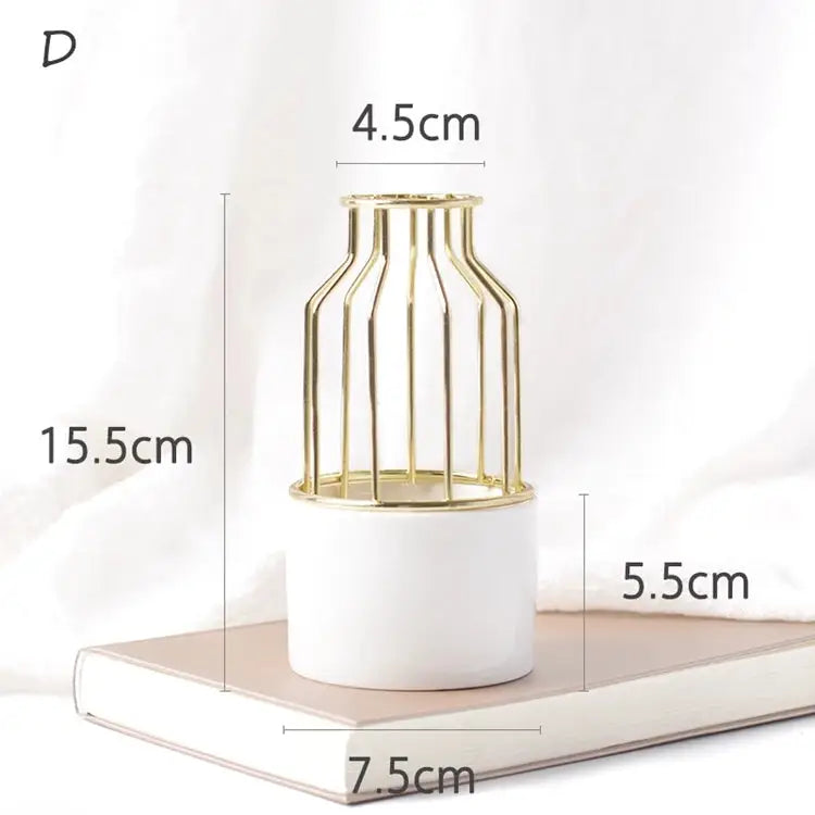 a white vase with a gold cage on top of it