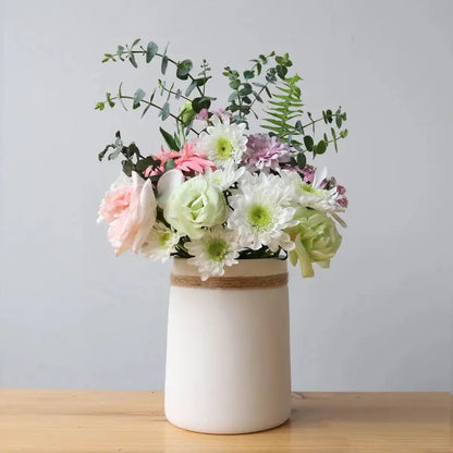 a white vase filled with flowers on top of a wooden table