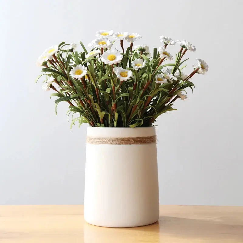 a white vase filled with white flowers on top of a wooden table