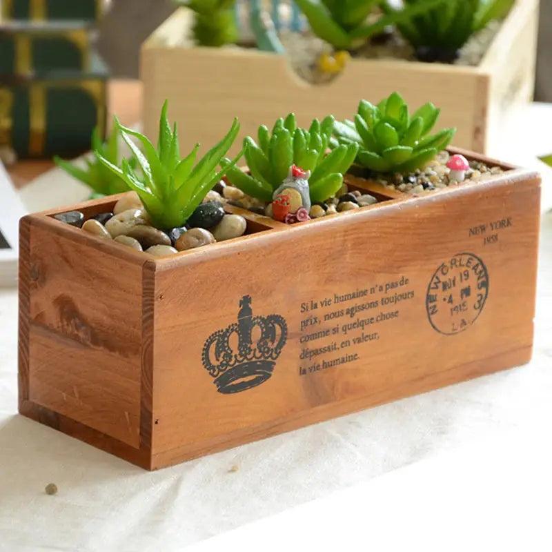 a wooden box filled with plants on top of a table