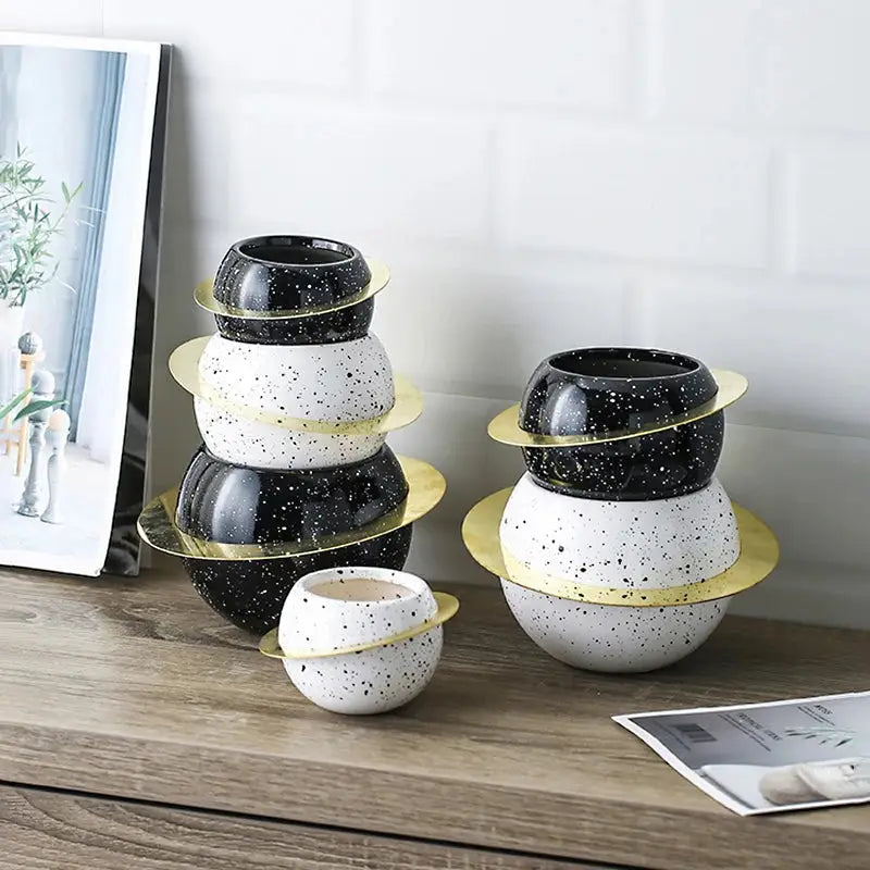 a wooden table topped with three black and white vases