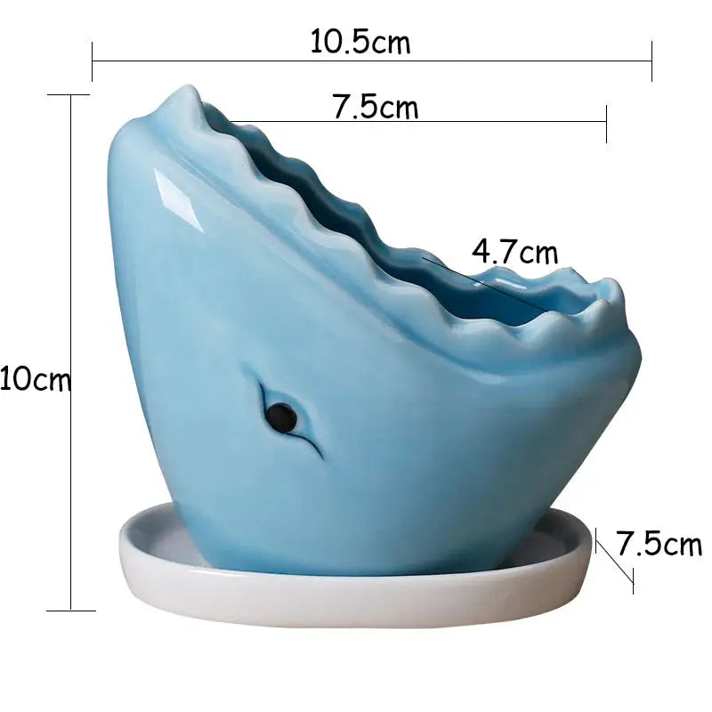 a blue whale shaped vase sitting on top of a white plate