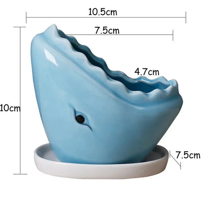 a blue whale shaped vase sitting on top of a white plate