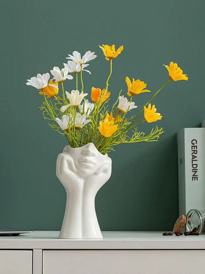 a white vase filled with yellow and white flowers