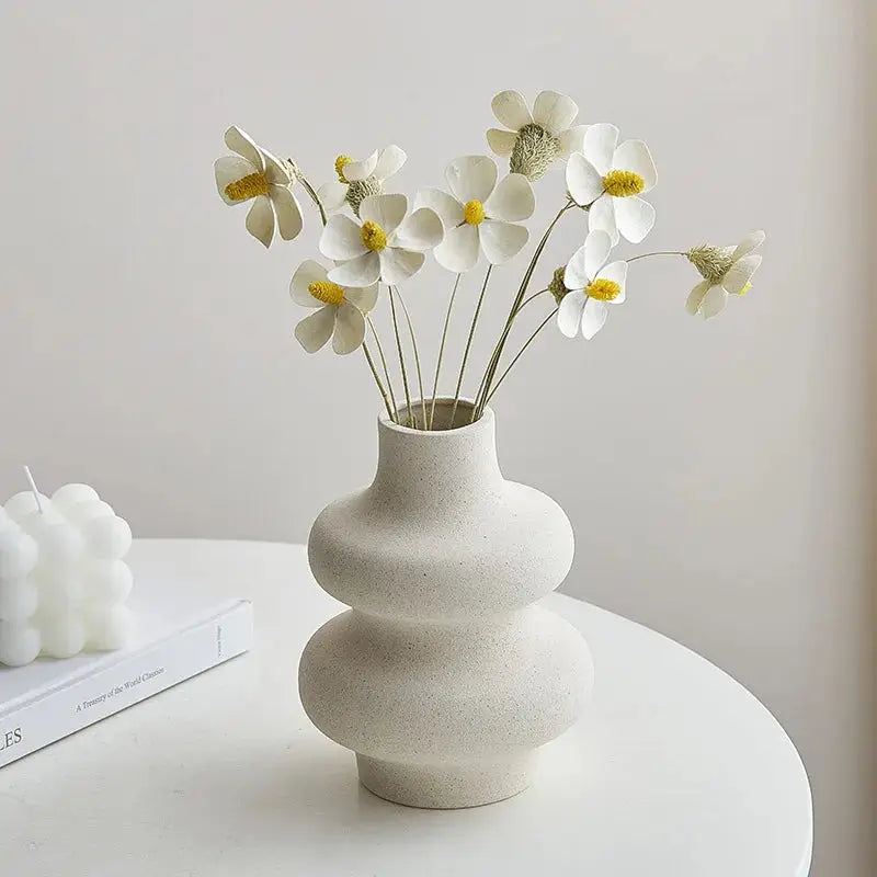 a white vase filled with white flowers on top of a table