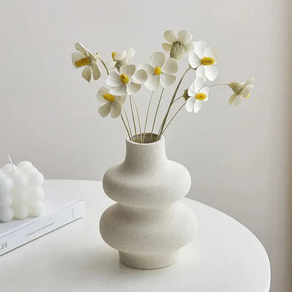 a white vase filled with white flowers on top of a table