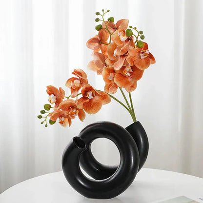 a black vase with flowers in it on a table