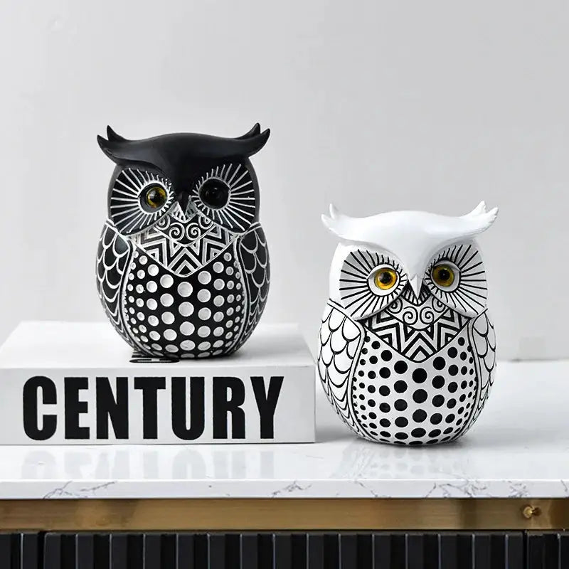 two black and white owls sitting on top of a table