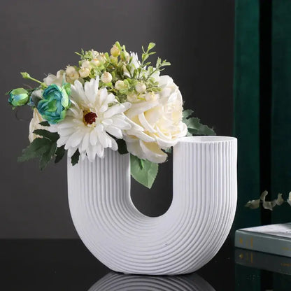 a white vase with flowers in it sitting on a table