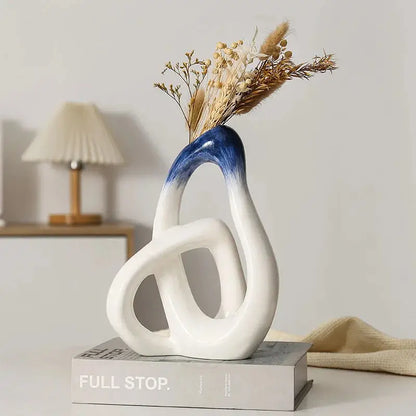 a white and blue vase sitting on top of a book