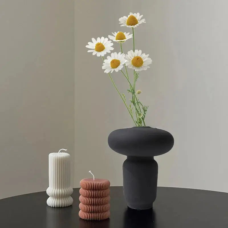a vase with daisies in it sitting on a table next to a stack of