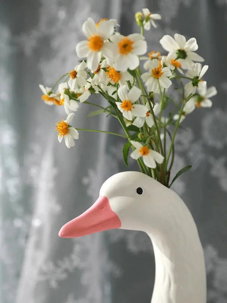 a duck vase with daisies and daisies in it