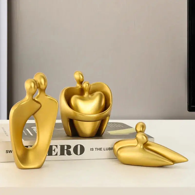 a couple of gold sculptures sitting on top of a book