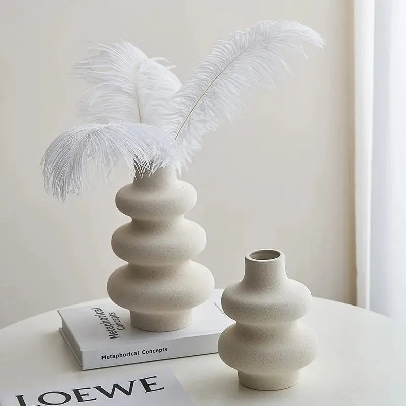 a white vase with a white feather on top of it