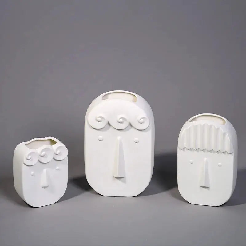 a group of three white vases sitting on top of a table