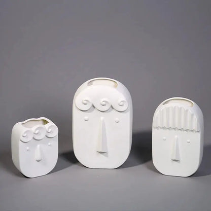 a group of three white vases sitting on top of a table