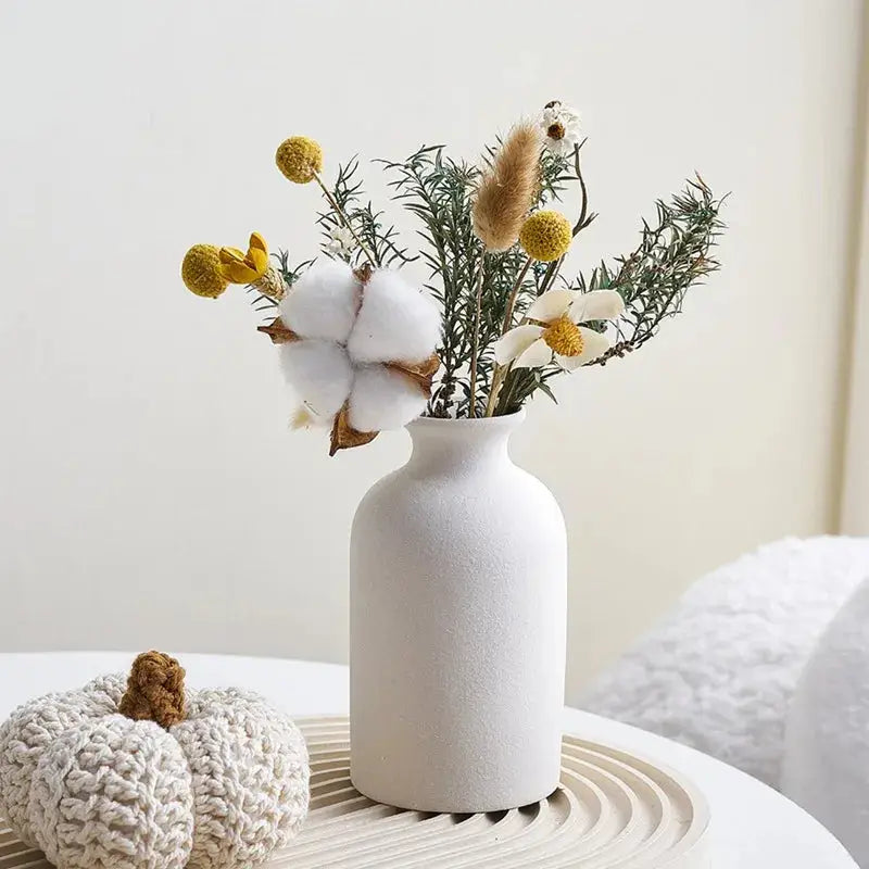 a white vase filled with flowers on top of a table