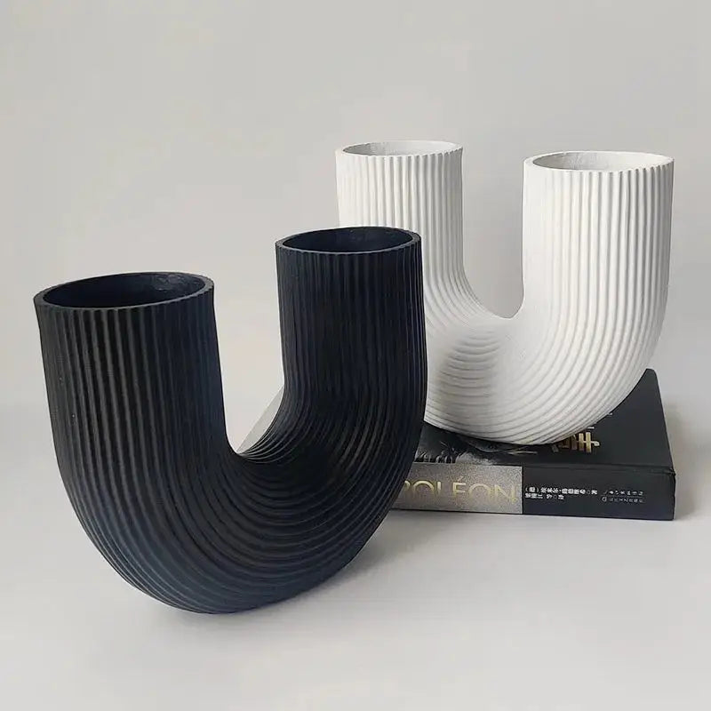 a couple of black and white vases sitting on top of a book