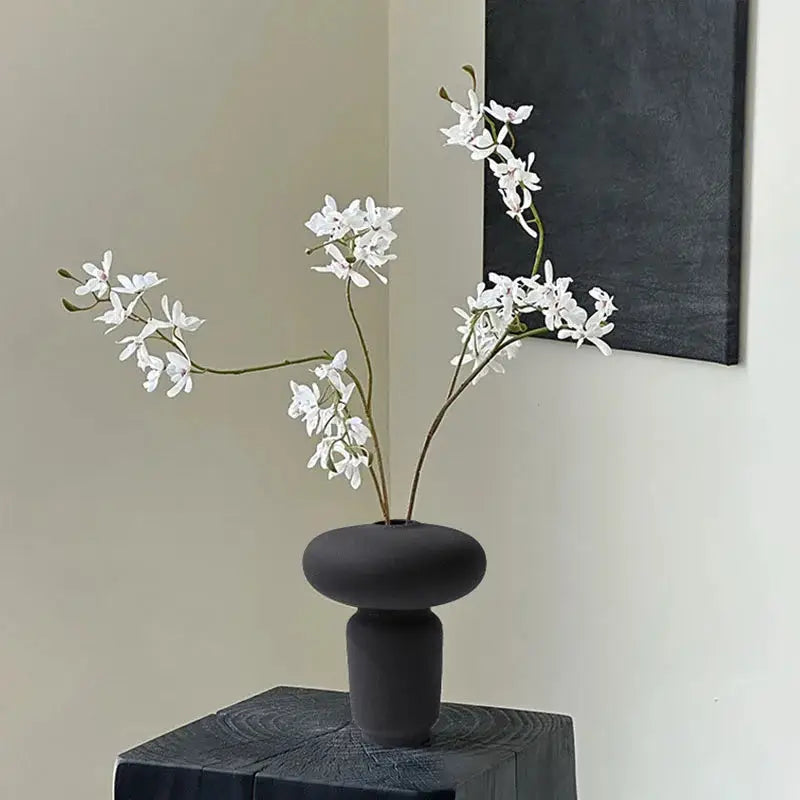 a black vase with white flowers in it