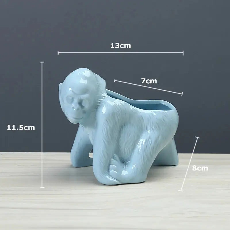 a blue monkey planter sitting on top of a wooden table