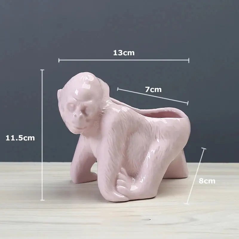 a pink monkey planter sitting on top of a wooden table