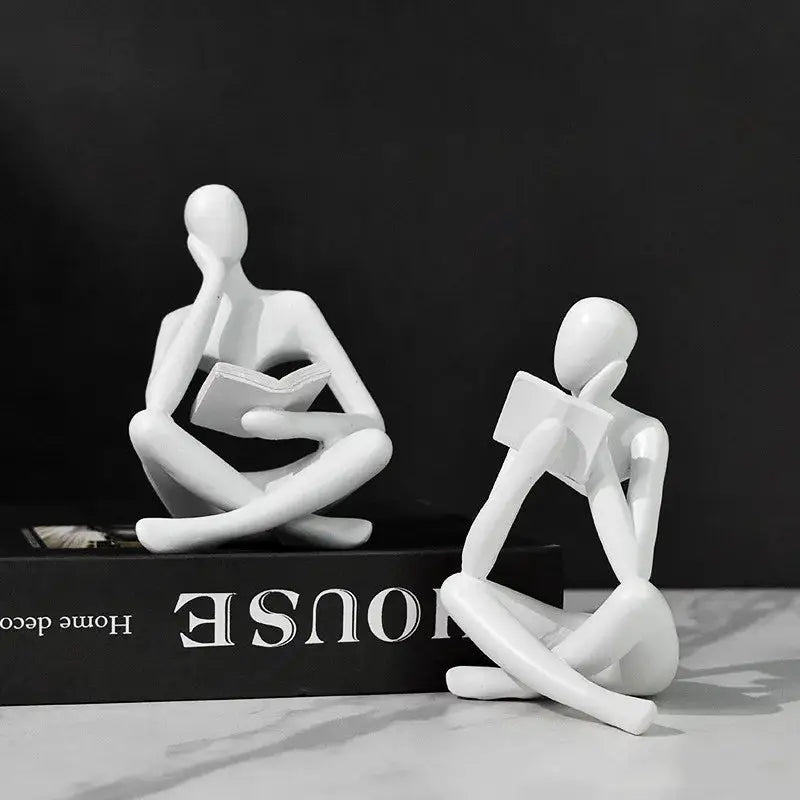 a couple of white figurines sitting on top of a book