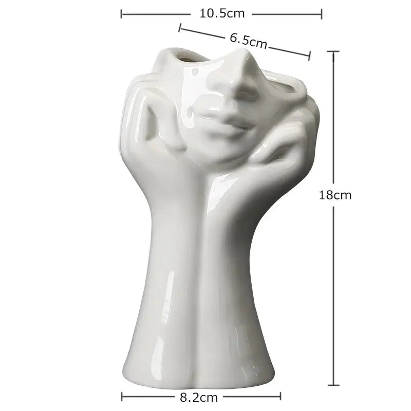 a white vase with a hand holding a face