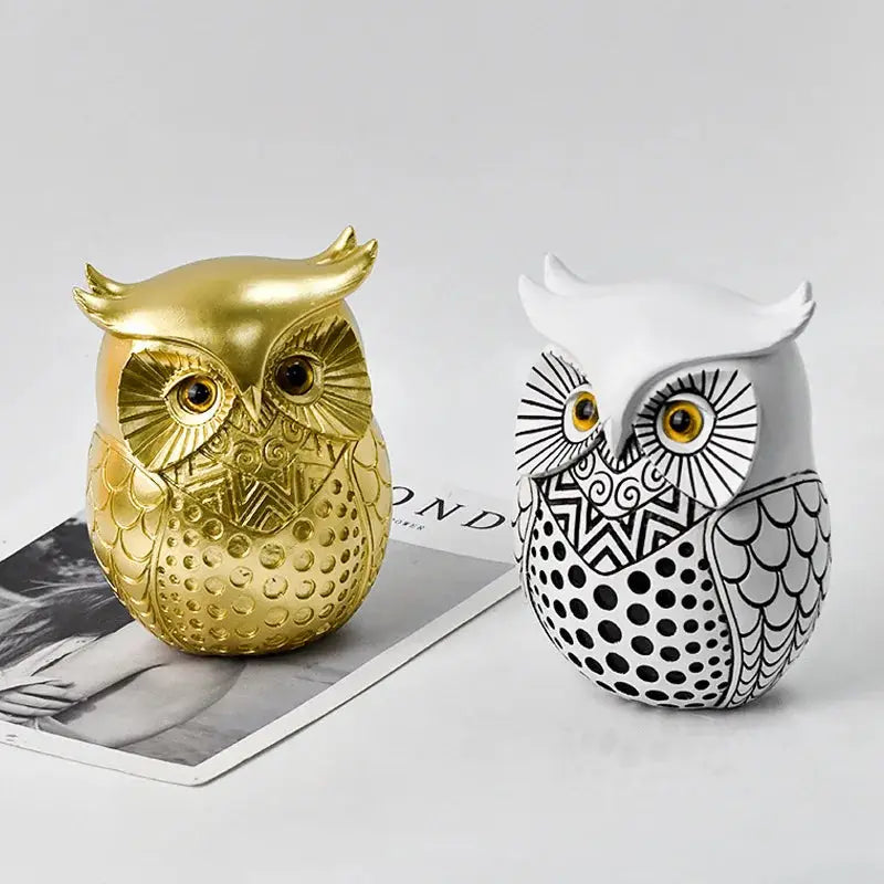 two gold and white owl figurines sitting on top of each other