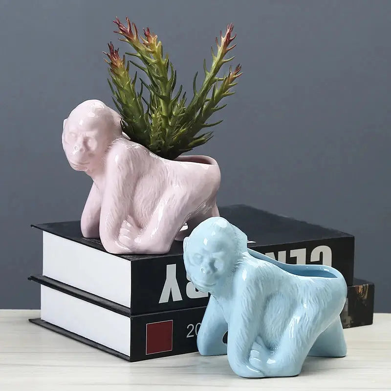 a couple of ceramic elephants sitting next to a plant