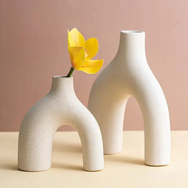 a white vase with a yellow flower in it