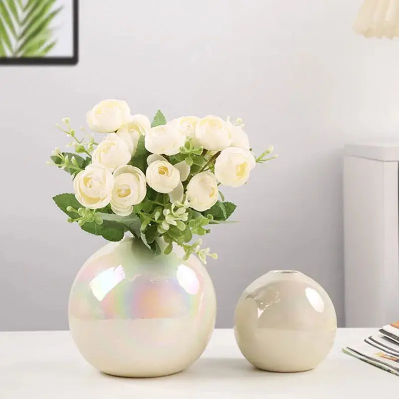 a white vase with white roses in it on a table