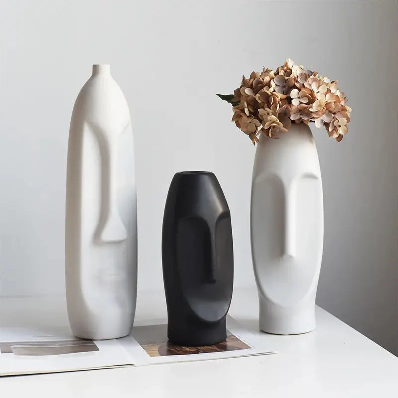 three white and black vases sitting on a table