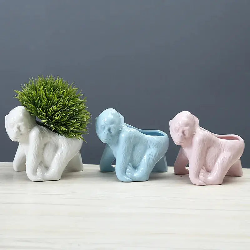 three small ceramic elephants are sitting next to a potted plant