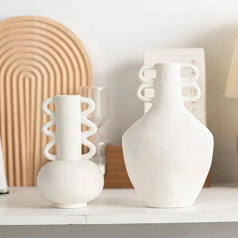 a couple of white vases sitting on top of a white shelf