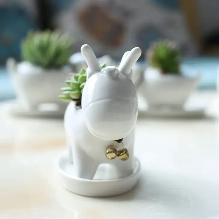 a white ceramic animal with a gold bell on it's neck