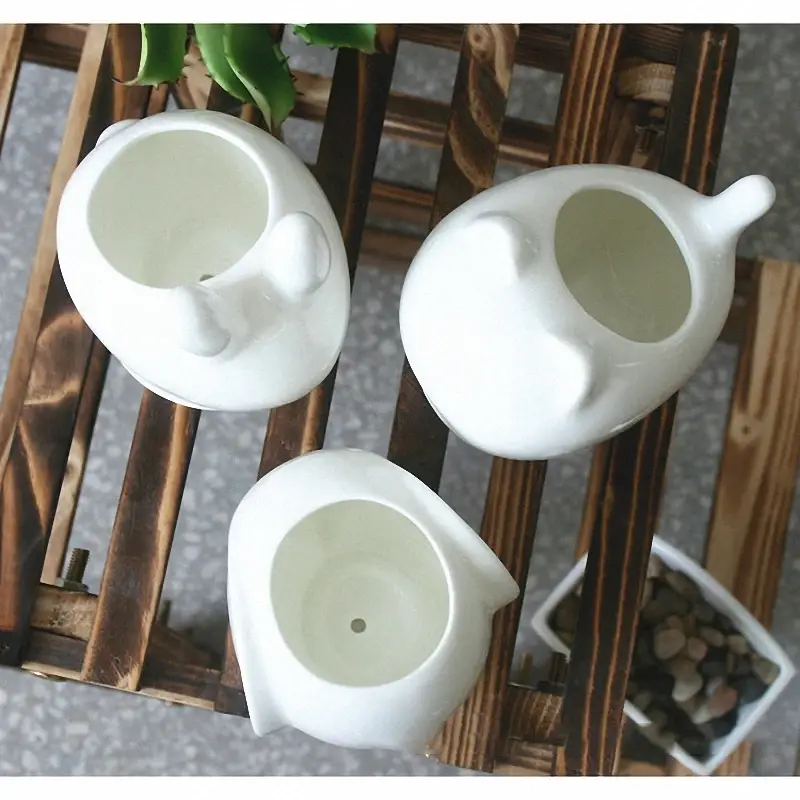 three white teapots sitting on top of a wooden rack