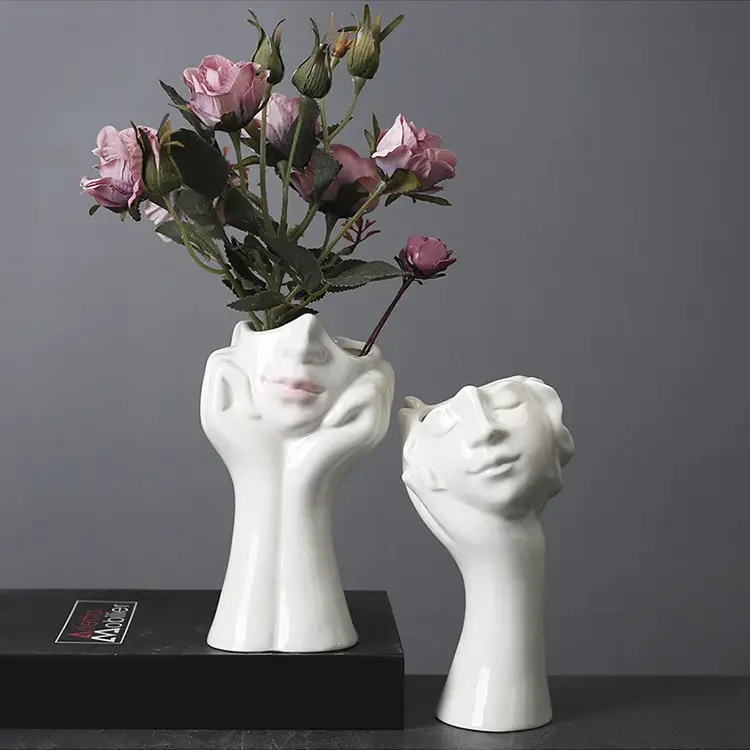 a couple of white vases with flowers in them